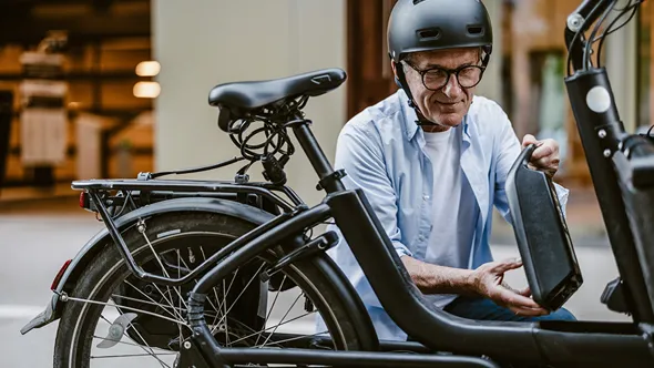 Manlig cyklist som hanterar sin cykels batteri.