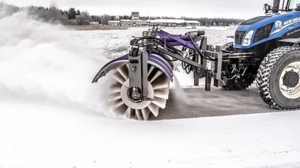 Sopvals på traktor borstar bort snö från cykelväg.