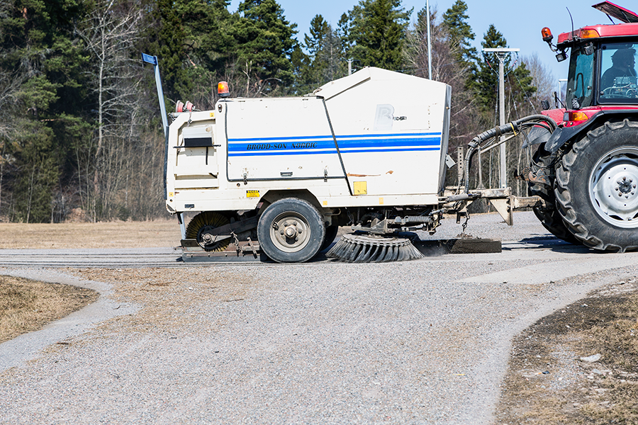 Sopmaskin sopar upp grus från asfalt på våren. Gruset innebär halkrisk.